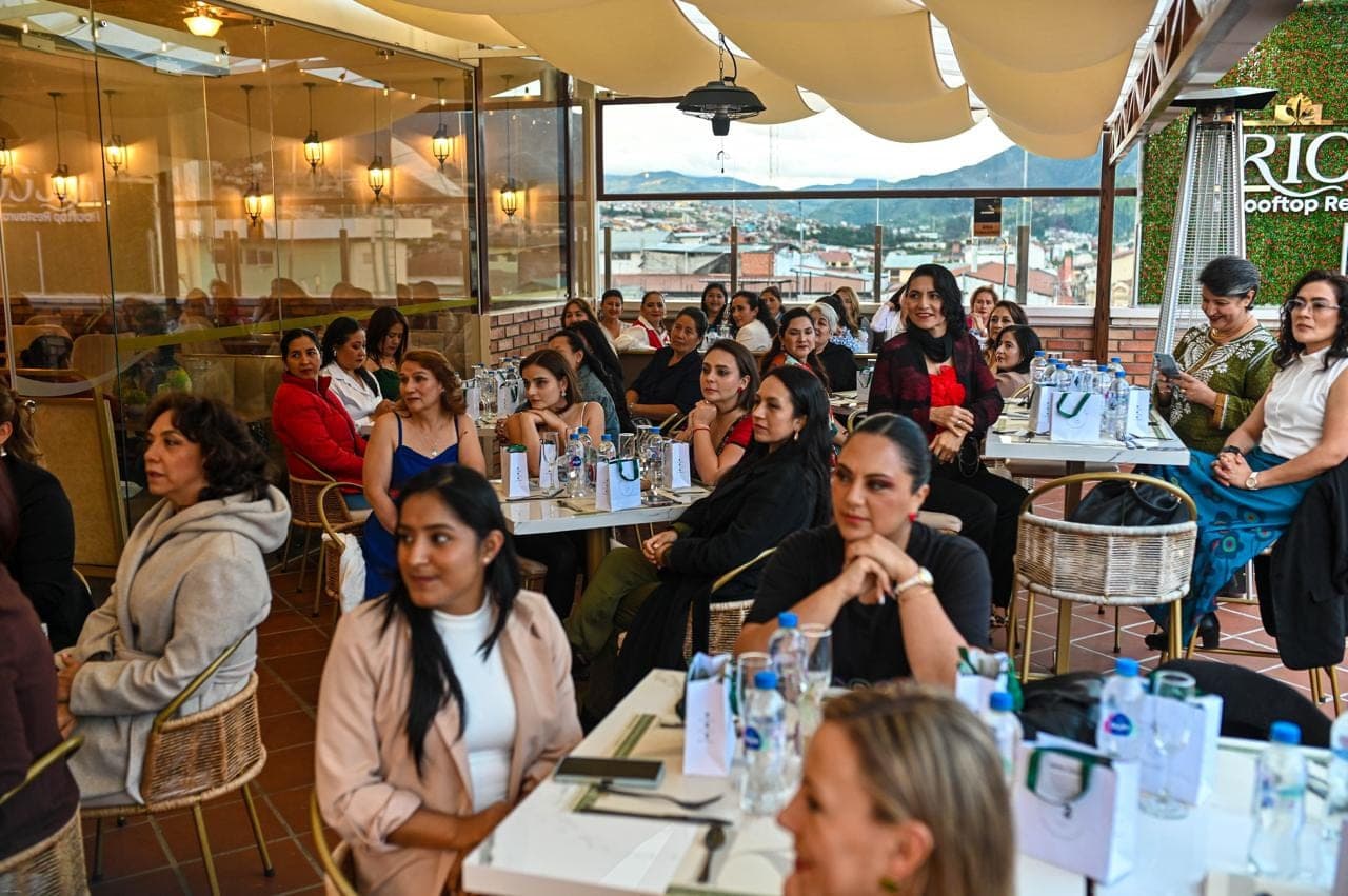 Mujeres sentadas alrededor de mesas escuchando durante un conversatorio en Loja